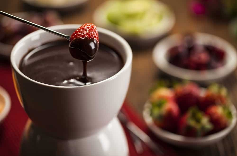 A strawberry being dipped in chocolate fondue.